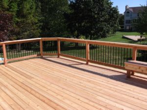 Deck & Fence Company Des Peres MO Wood deck with rail system overlooking green grass in expansive backyard