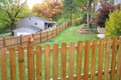 Deck and Fence Company Clarkson Valley, MO Closeup of a wood fence that enclosed a yard. A house and trees are visible in the background