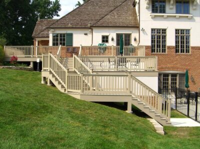 Deck and Fence Company Clayton, MO A khaki composite deck with a staircase sits in front of a white and brick house.